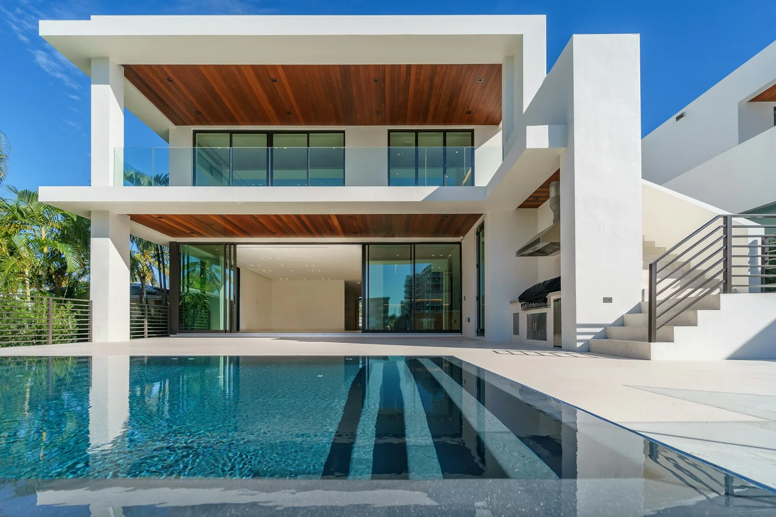 Large dark-framed windows and open patio glazing on a white contemporary home