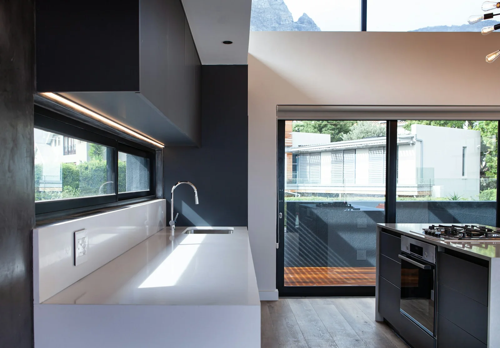 Modern kitchen with black-framed windows and a sliding glass door opening to a deck