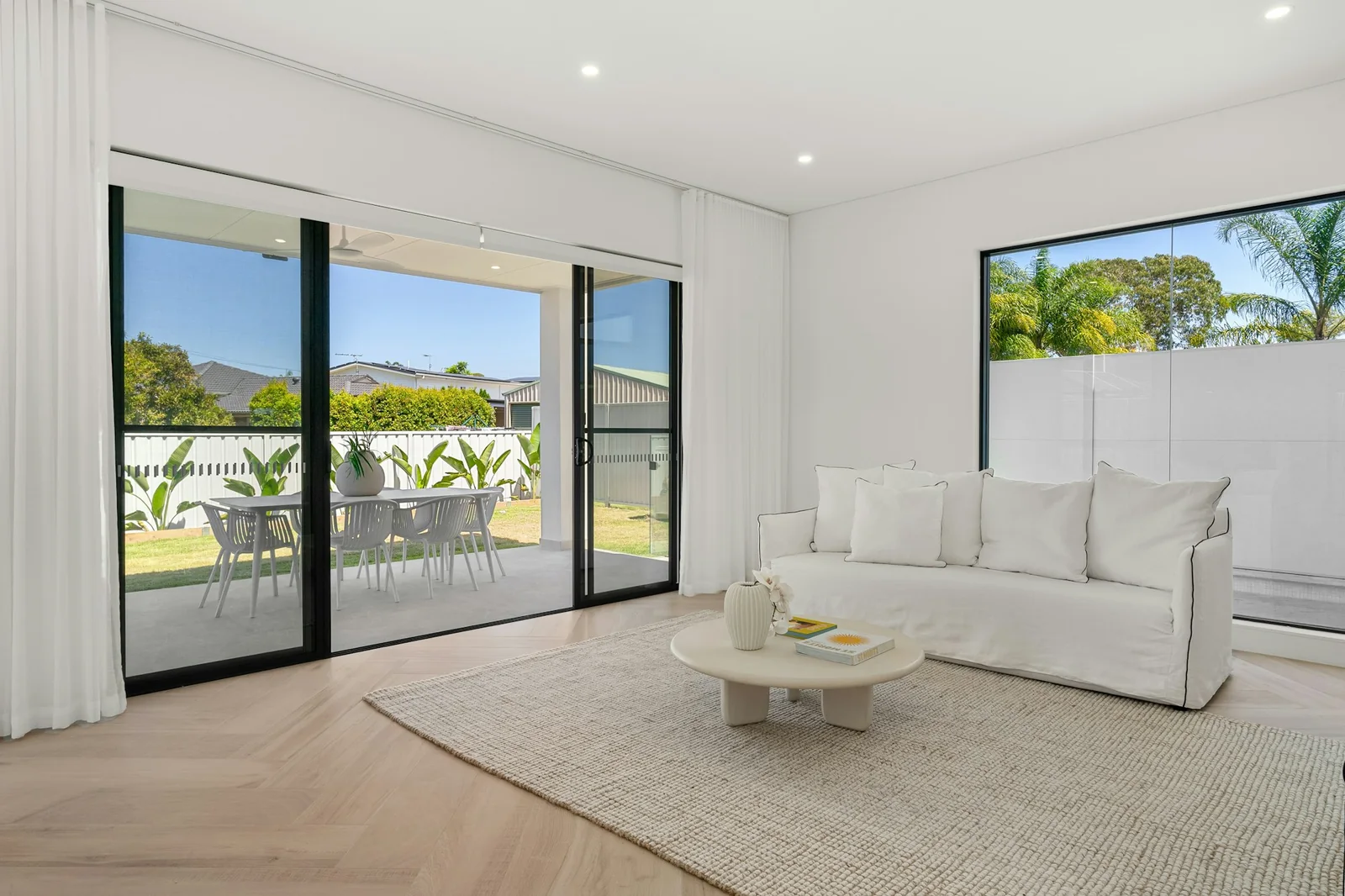 Black-framed sliding glass doors connecting a bright living room to a covered garden terrace